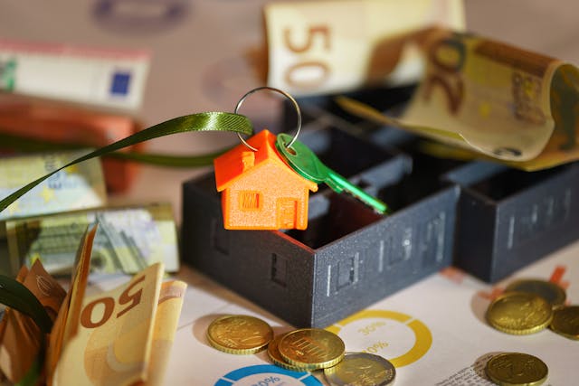 a small house keychain surrounded by coins and cash