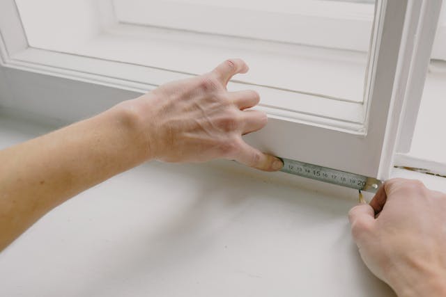 someone measuring a window pane