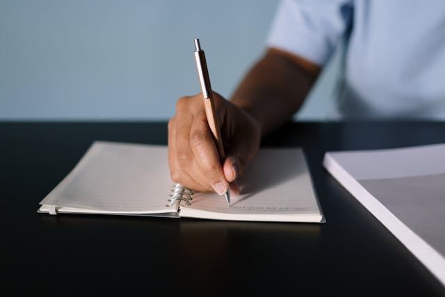 Close-Up Shot of a Person Writing on a Notebook