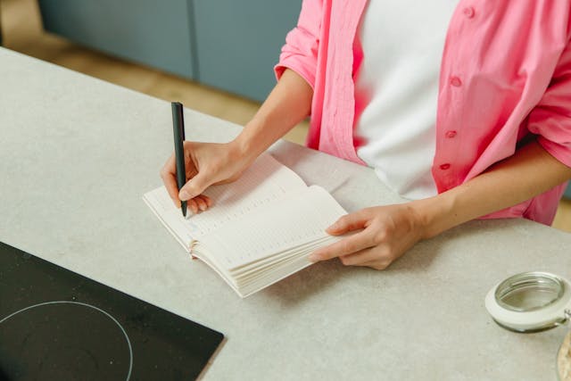 person Writing on Notebook